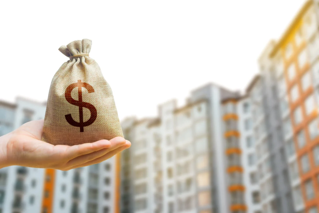 Hand holding a money bag in front of apartment buildings